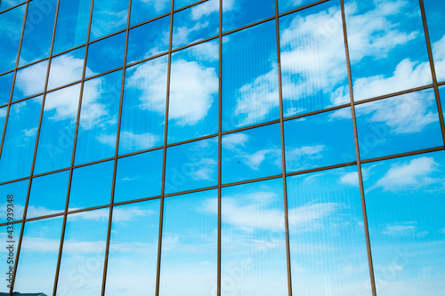Blue sky with snow-white clouds reflected in the glass of the building. Backgrounds  structures  and designs.