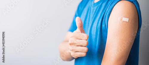 Happy man showing her arm with bandage after receiving vaccine. Vaccination, immunization, inoculation and Coronavirus ( Covid-19 ) pandemic