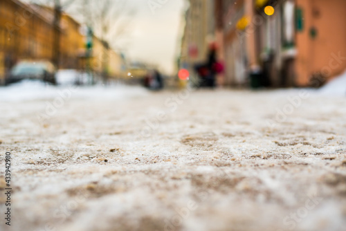 Snowy winter in the big city, people go on snow-covered street. Close up view from the sidewalk level