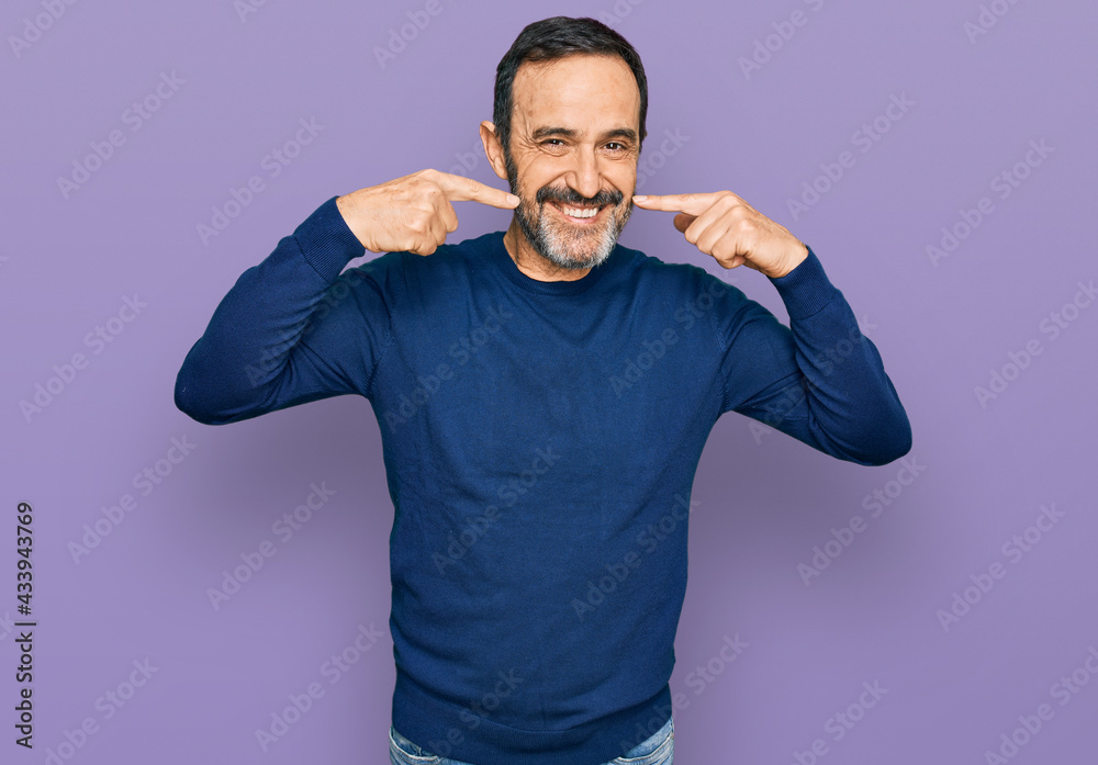 Fototapeta premium Middle age hispanic man wearing casual clothes smiling cheerful showing and pointing with fingers teeth and mouth. dental health concept.