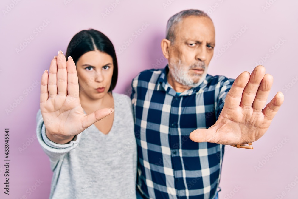 Hispanic father and daughter wearing casual clothes doing stop sing with palm of the hand. warning expression with negative and serious gesture on the face. Hispanic father and daughter wearing casual clothes doing stop sing with palm of the hand. warning expression with negative and serious gesture on the face.