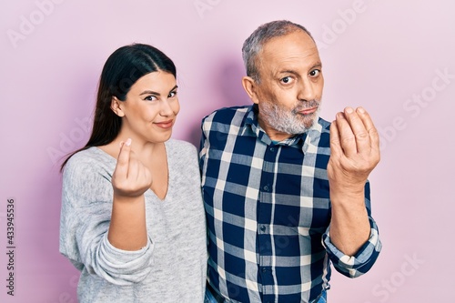 Hispanic father and daughter wearing casual clothes doing money gesture with hands, asking for salary payment, millionaire business