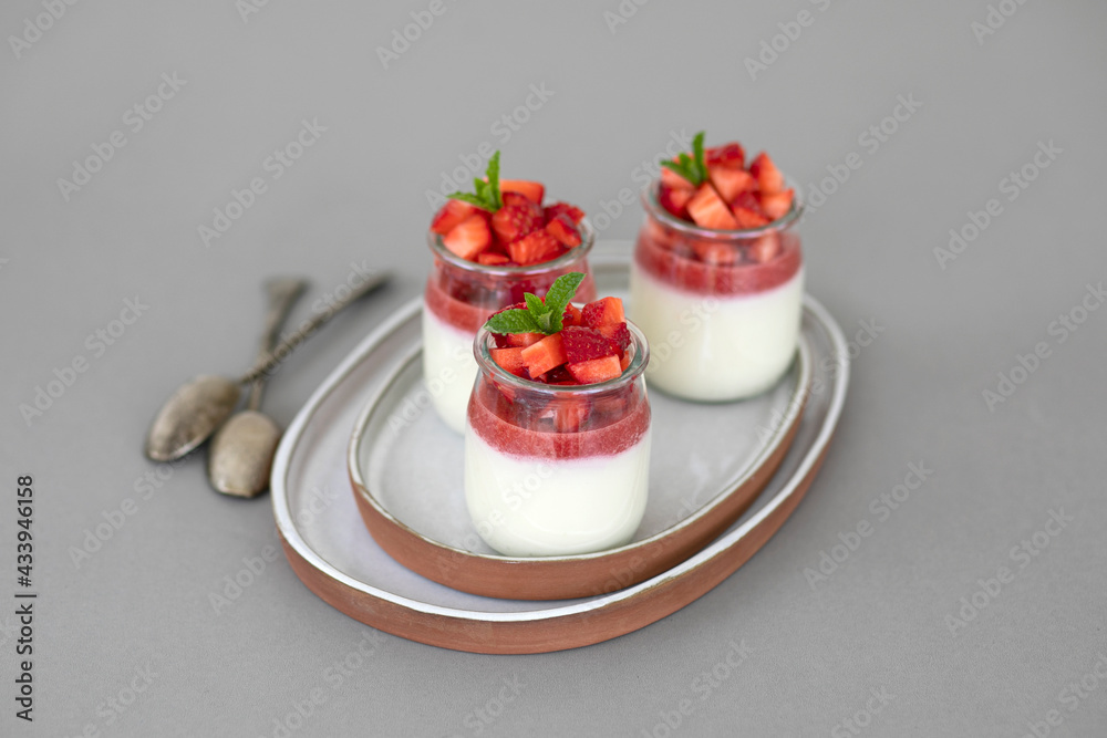 Italian dessert panna cotta with fruit jelly and fresh pieces of strawberries on gray background. Copy space Italian dessert panna cotta with fruit jelly and fresh pieces of strawberries on gray background. Copy space