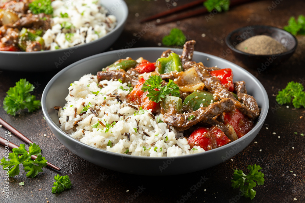 Stir fry Chinese pepper beef steak with onion, red and green bell pepper, rice in bowl Stir fry Chinese pepper beef steak with onion, red and green bell pepper, rice in bowl