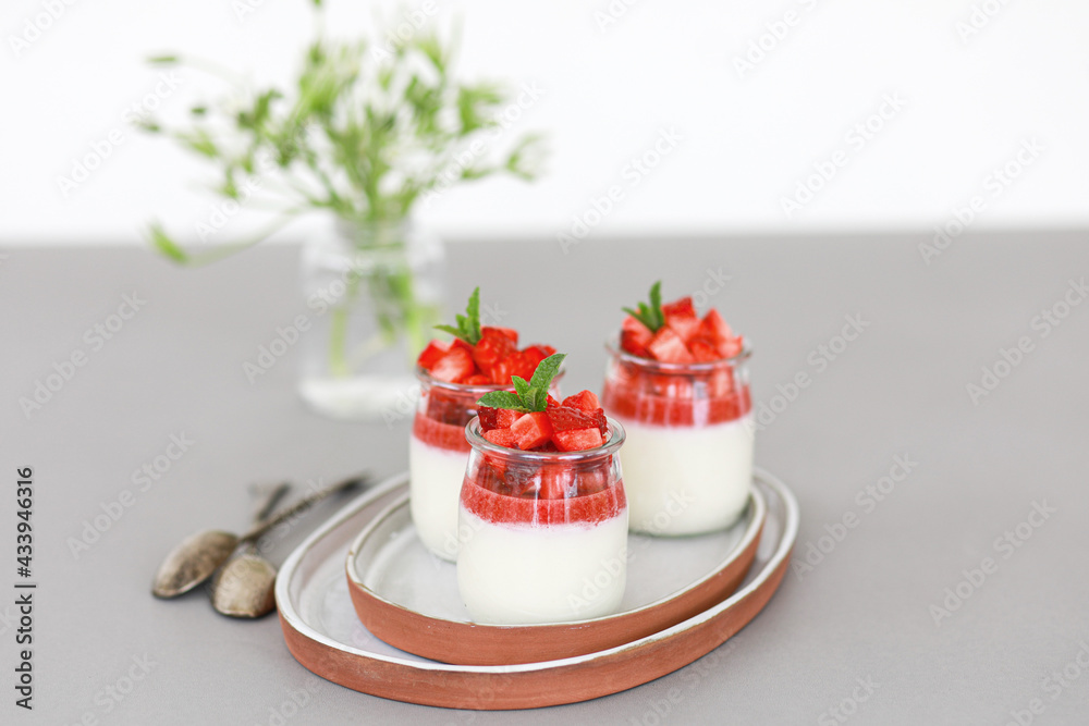 Italian dessert panna cotta with fruit jelly and fresh pieces of strawberries on gray background. Copy space Italian dessert panna cotta with fruit jelly and fresh pieces of strawberries on gray background. Copy space