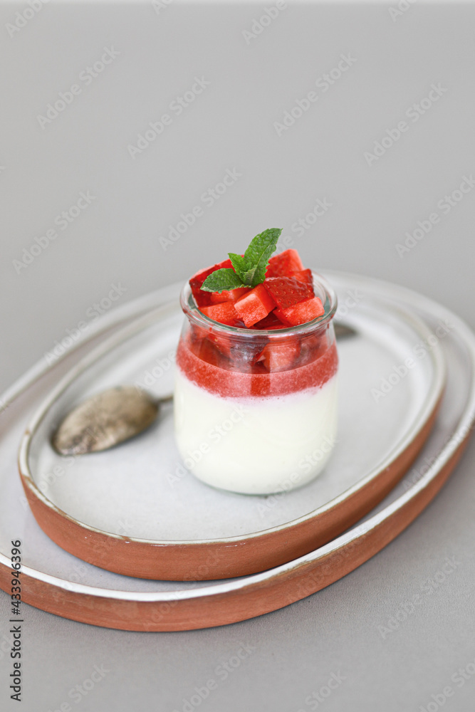 Italian dessert panna cotta with fruit jelly and fresh pieces of strawberries on gray background. Copy space Italian dessert panna cotta with fruit jelly and fresh pieces of strawberries on gray background. Copy space