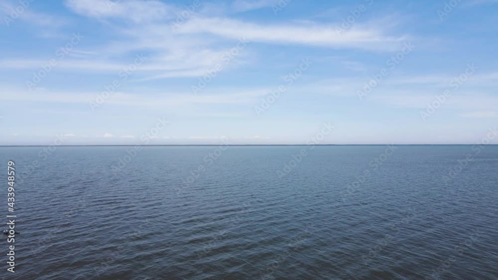 Drone flying forward just above the water of a large blue lake with a blue sky and scattered white clouds.
Drone flying forward just above the water of a large blue lake with a blue sky and scattered white clouds.