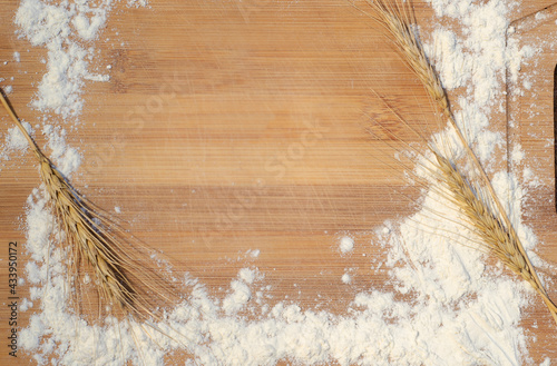 Top view background with a wooden desk and flour with wheat spikelets as a frame. Copyspace