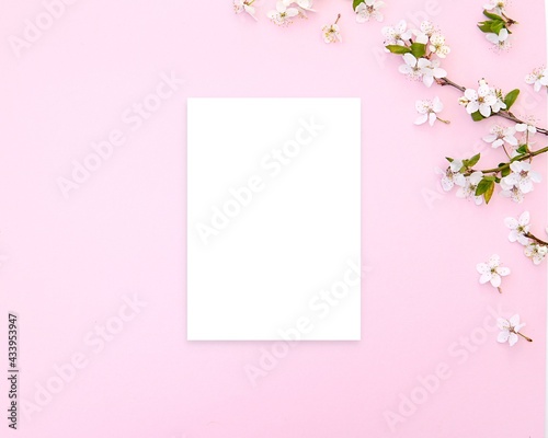 Greeting card, invitation, letter, note paper mockup on pink feminine background with spring blooming branches, empty vertical card.