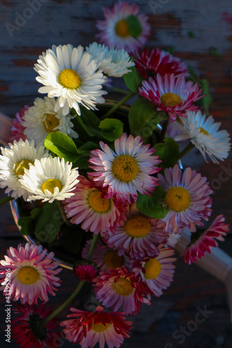 beautiful summer flowers in an iron watering can on a wooden background