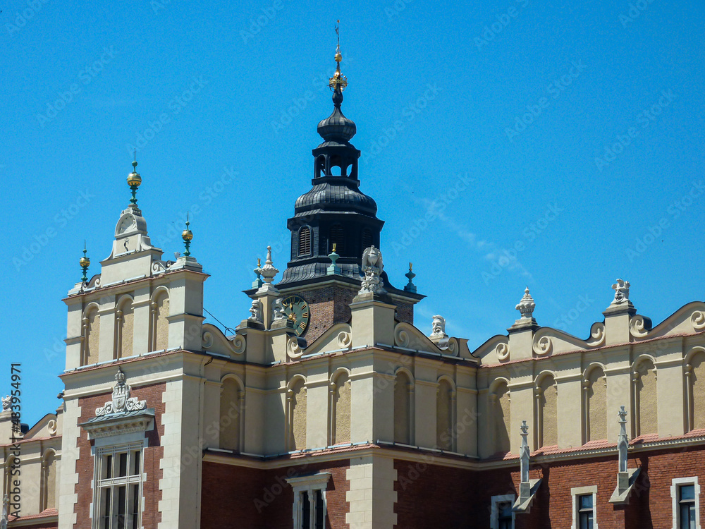 A close up on the rooftop of The Krak?w Cloth Hall in Cracow, Poland. There is one high tower on top. Medieval architectural style. Clear and blue sky. - obrazy, fototapety, plakaty 