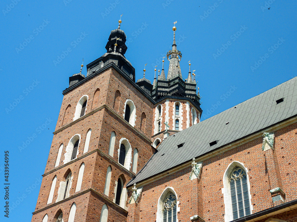 A side view on St. Mary's Basilica in Cracow, Poland. The two bell towers od the basilica are towering above the city. Clear and blue sky. A side view on St. Mary's Basilica in Cracow, Poland. The two bell towers od the basilica are towering above the city. Clear and blue sky.