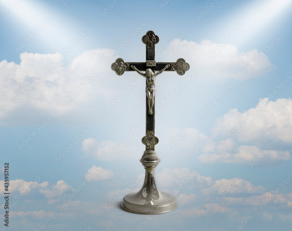 Cross in heaven. A statuette of crucified Jesus. The symbol of the Christian religion against a blue sky with clouds. Salvation.