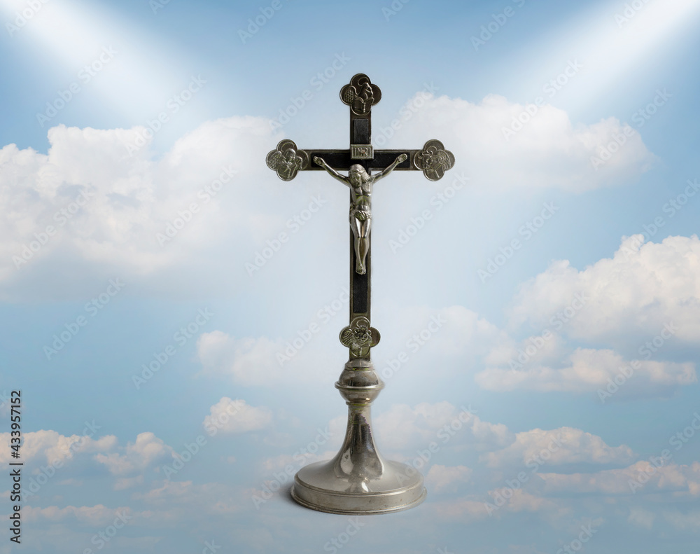 Cross in heaven. A statuette of crucified Jesus. The symbol of the Christian religion against a blue sky with clouds. Salvation. Cross in heaven. A statuette of crucified Jesus. The symbol of the Christian religion against a blue sky with clouds. Salvation.