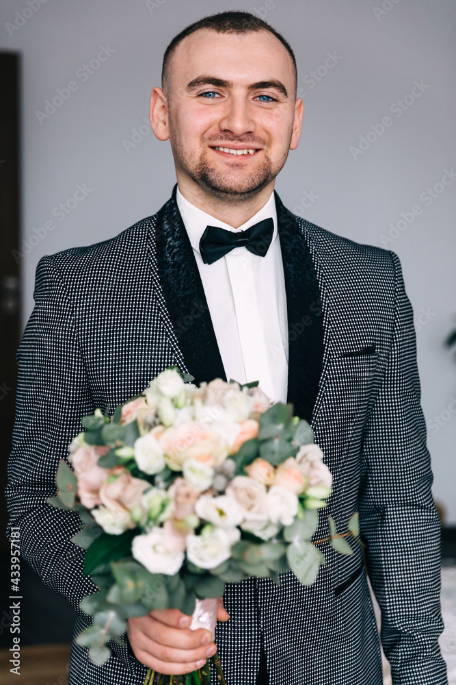 The groom holds a bouquet of flowers for the bride. stylish groom prepares in the morning for the wedding ceremony. Morning preparation of a man. The groom holds a bouquet of flowers for the bride. stylish groom prepares in the morning for the wedding ceremony. Morning preparation of a man.