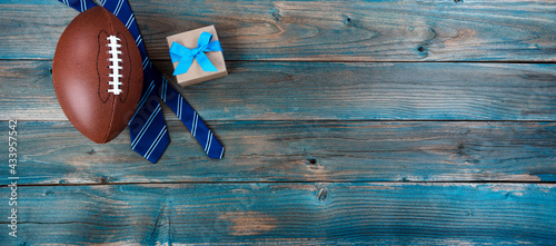 Football  necktie and giftbox on faded blue wood for happy fathers day concept