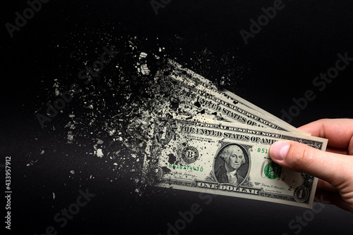 Inflation, dollar hyperinflation with black background. One dollar bill is sprayed in the hand of a man on a black background. The concept of decreasing purchasing power, inflation. photo