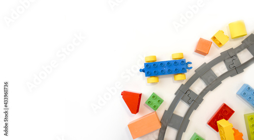 Colorful kids toys flat lay with toy train, railway, plastic and wooden blocks on white background. Children border educational for preschool , playground and kindergarden. Top view. Copyspace.