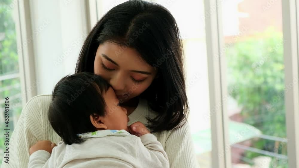 Happy young asian mom holding cute adorable infant child in livingroom. Cheerful adult mother lull a kid baby having love together in home. Parents and daughter activity, Happy young asian mom holding cute adorable infant child in livingroom. Cheerful adult mother lull a kid baby having love together in home. Parents and daughter activity,