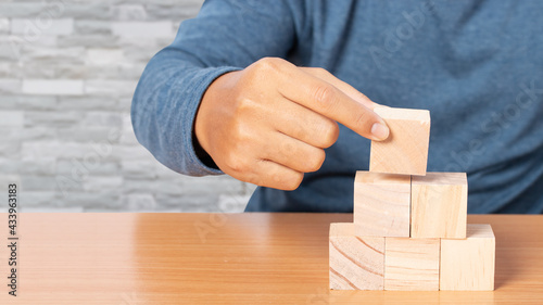 Young man stacking wooden blocks. Business development concept.
