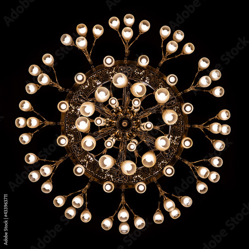 Looking straight up at a lit chandelier. Beautiful bulb chandelier in interier on black backgroun. photo
