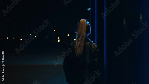 View from behind. A girl in a leather jacket walks along