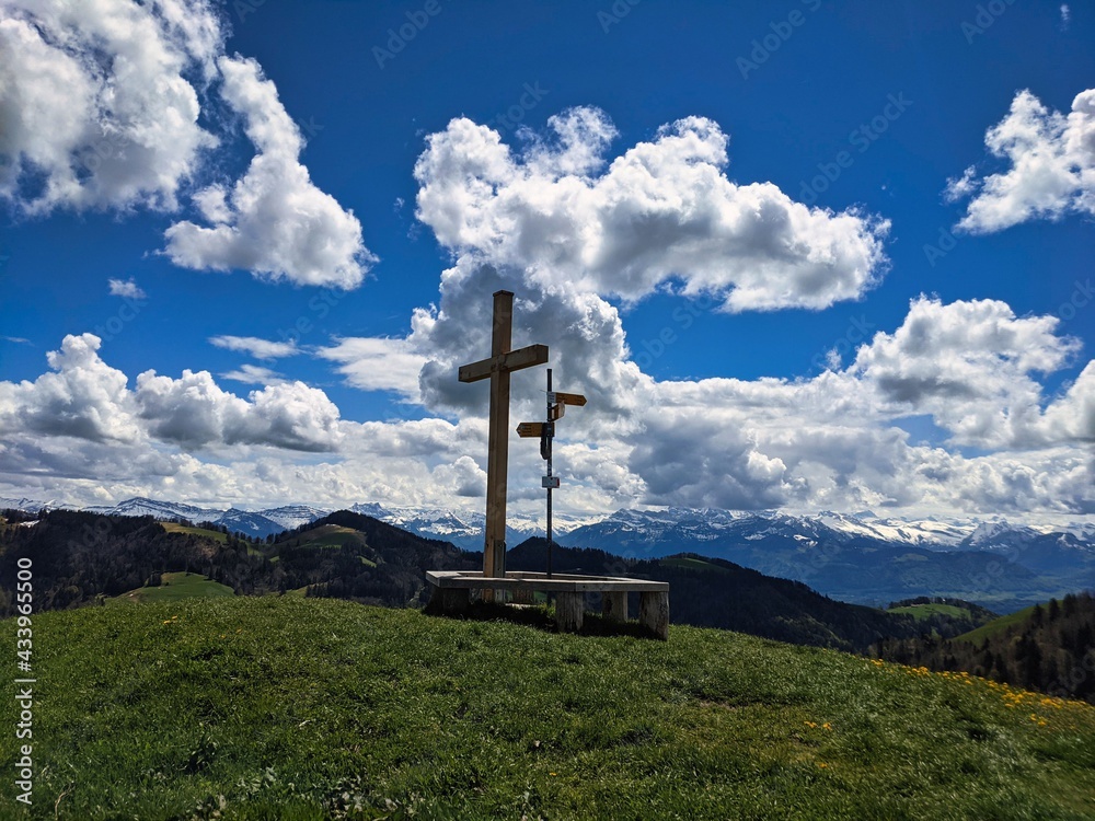summit cross on the beautiful grass hill huettchopf in zurich oberland switzerland. Nice view of the mountains. bench summit cross on the beautiful grass hill huettchopf in zurich oberland switzerland. Nice view of the mountains. bench