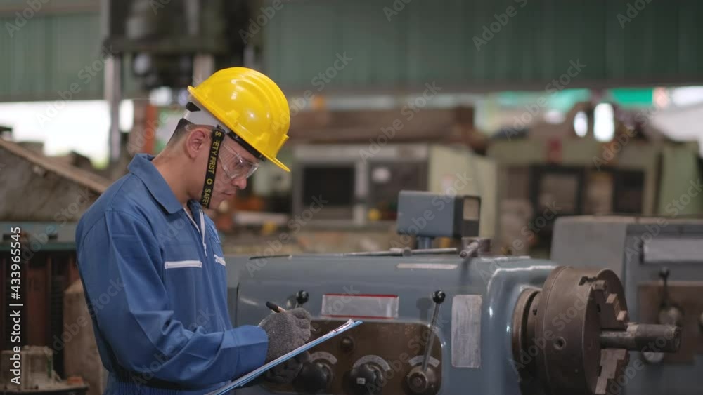 Factory man or technician worker with blue uniform and yellow hardhat check the function of machine and record the data in workplace area. Factory man or technician worker with blue uniform and yellow hardhat check the function of machine and record the data in workplace area.