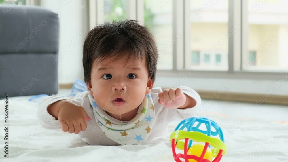 Happy asian baby infant learning to crawl on bed. Newborn baby, Care and Love. Raising Newborn in the family. Happy asian baby infant learning to crawl on bed. Newborn baby, Care and Love. Raising Newborn in the family.