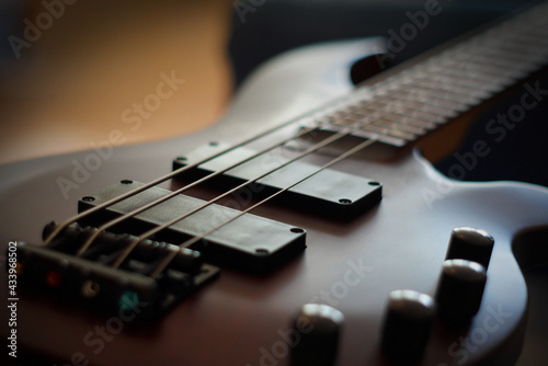 Closeup shot of a smooth body, pickups, bridge, knobs and strings of a bass guitar musical instrument with backlight © Vadim Rodnev