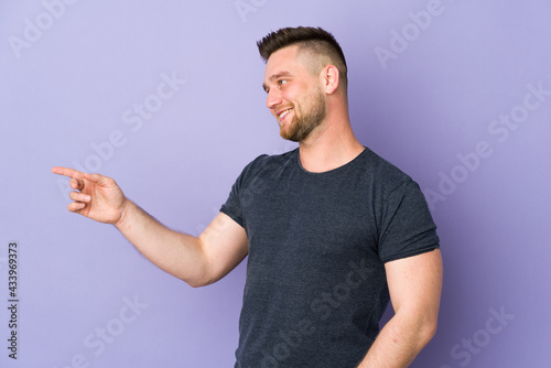 Russian handsome man over isolated background pointing finger to the side and presenting a product