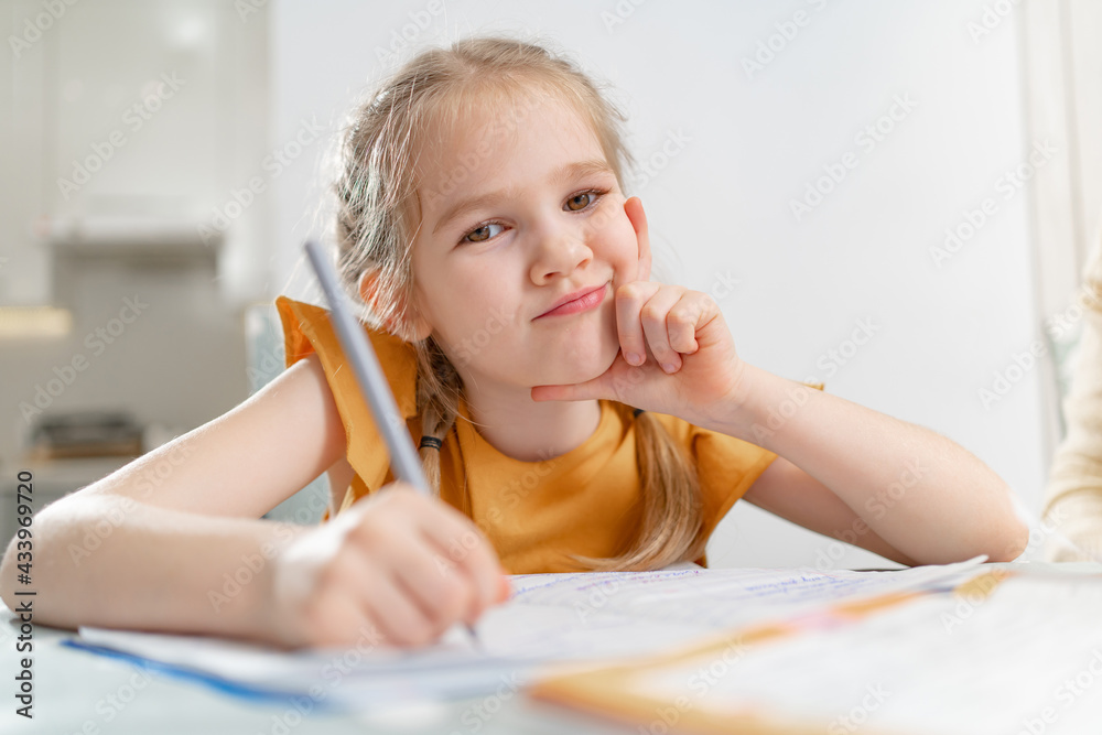 A thoughtful little schoolgirl does her homework. complexities of correct and beautiful handwriting. there is no desire to learn. family and distance learning A thoughtful little schoolgirl does her homework. complexities of correct and beautiful handwriting. there is no desire to learn. family and distance learning