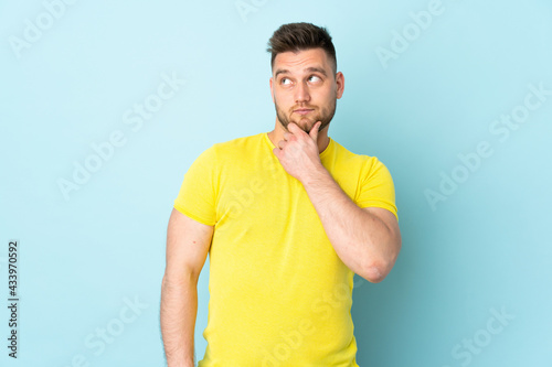Russian handsome man isolated on blue background thinking an idea while looking up