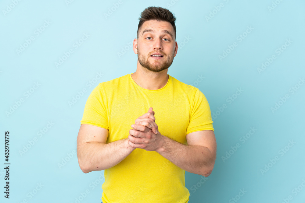 Russian handsome man isolated on blue background laughing