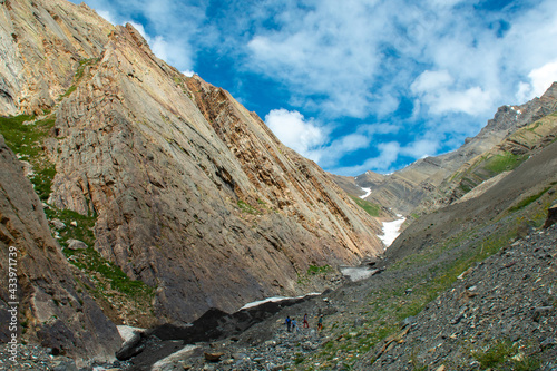 people hiking on a rocky and snowy mountain with a sky background