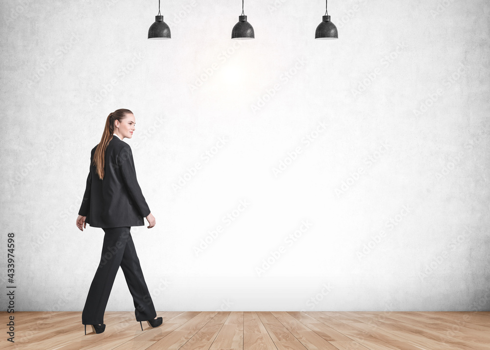 Fototapeta premium Businesswoman walking on grey background on parquet floor, mockup empty wall