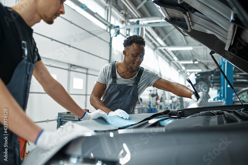 Two male mechanics inspects engine, car service