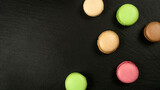 Multicolored macarons on black background with copy space top view