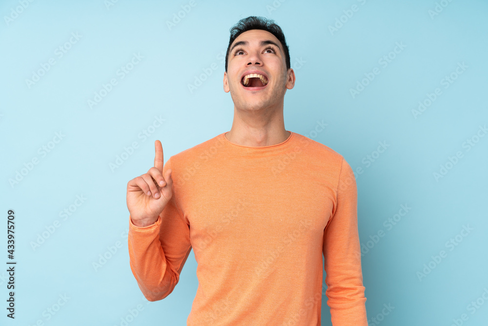Young caucasian handsome man isolated on blue background pointing up and surprised Young caucasian handsome man isolated on blue background pointing up and surprised
