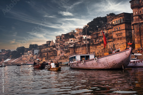 Varanasi, India: Dramatic sunset in a holy hindu place of worship with lots of tourists on boats and ancient architecture ghat located in Uttar pradesh. photo