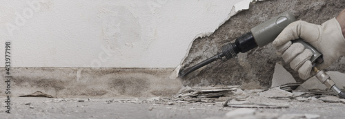 Foto house renovation concept, construction worker breaks the old plaster of the wall