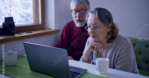 elderly couple understands how the computer works, husband and wife put on glasses to understand laptop