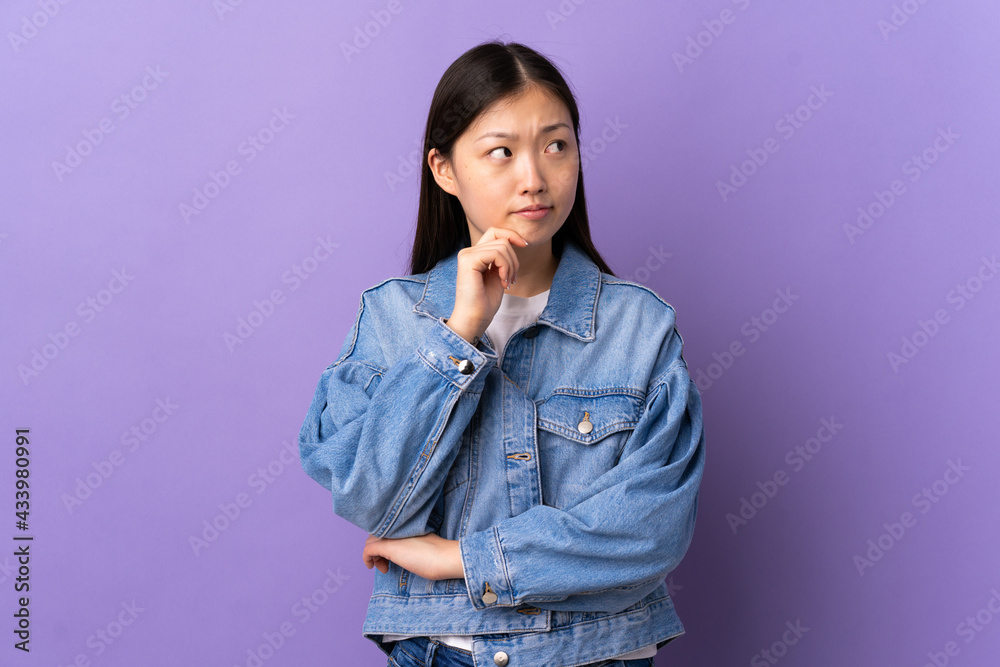 Young Chinese girl over isolated purple background having doubts and thinking Young Chinese girl over isolated purple background having doubts and thinking