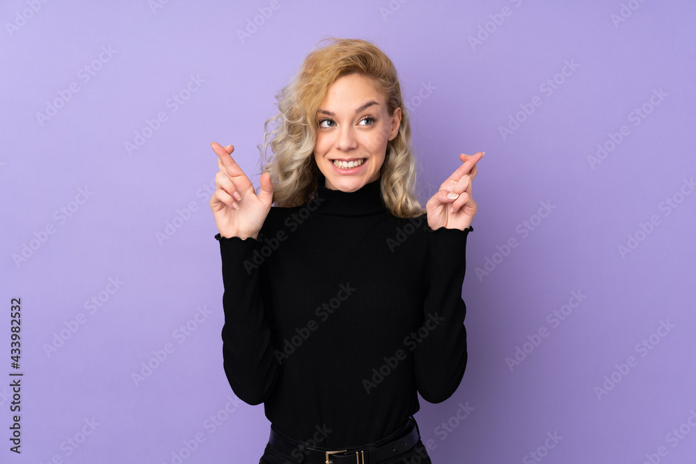 Young blonde woman isolated on purple background with fingers crossing Young blonde woman isolated on purple background with fingers crossing
