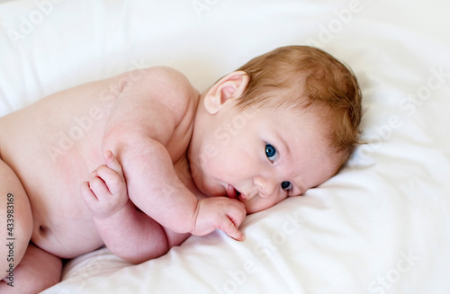Cute happy 3 month baby boy or girl lying on a white sheet