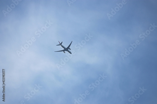 Airplane flying in the blue sky on background of white clouds. Twin-engine commercial plane, turbulence and travel concept