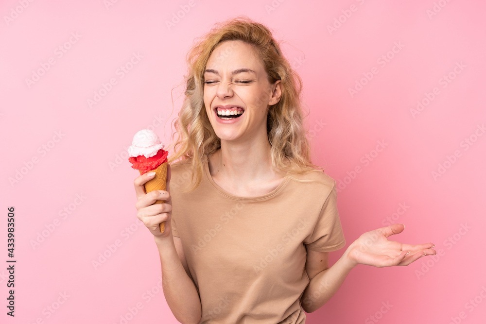 Young blonde woman holding a cornet ice cream isolated on pink background Young blonde woman holding a cornet ice cream isolated on pink background