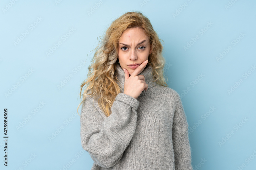 Young blonde woman wearing a sweater isolated on blue background thinking Young blonde woman wearing a sweater isolated on blue background thinking