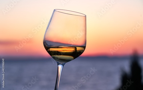 Canvastavla Close up image of glass of wine in woman's hand with the sea and sunset in the background