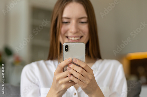 Happy young caucasian millennial woman web surfing information, chatting in social networks sitting on couch at home